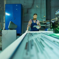 Workers Operating Laser Engraving Unit at Factory